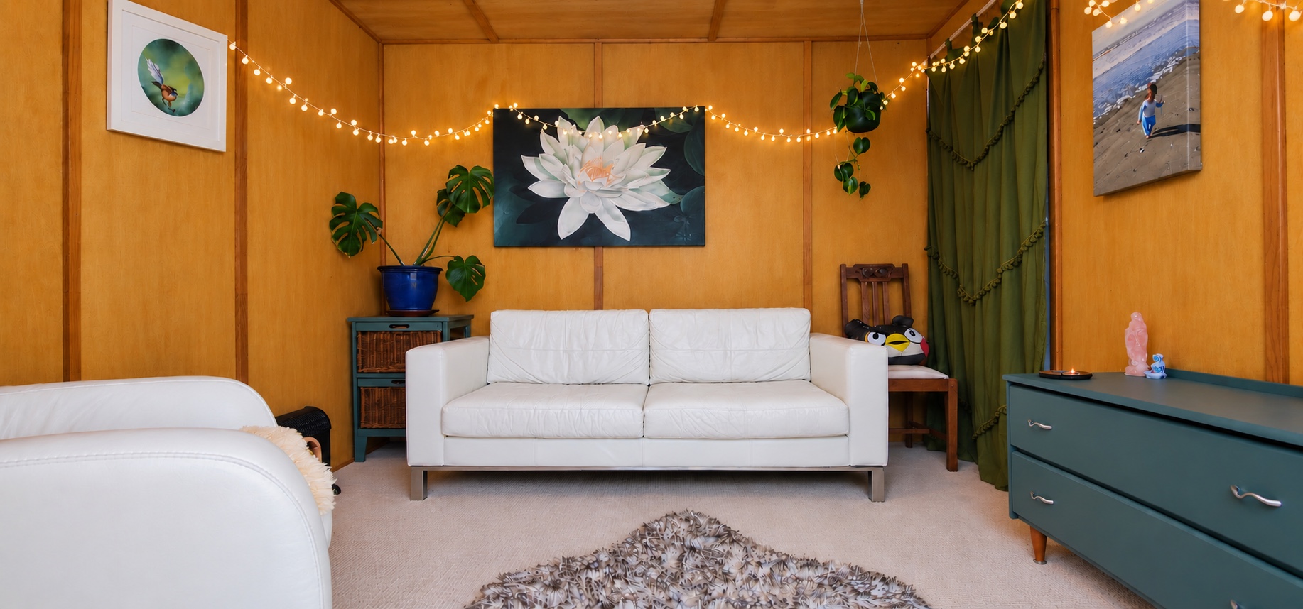 Anna's welcoming therapy room, with a white sofa, plants and warm wooden walls.